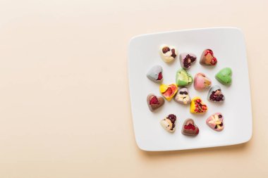 Plate with different chocolate on colored background. Assortment of fine chocolates top view vith copy space Health and obesity concept.