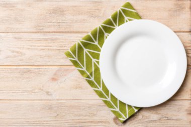 Renkli arka planda üst görünüm yiyecek için masa örtüsü üzerindeki boş yuvarlak beyaz tabak. Tasarımınız için boşluk olan peçeteye boş tabak.