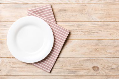 Renkli arka planda üst görünüm yiyecek için masa örtüsü üzerindeki boş yuvarlak beyaz tabak. Tasarımınız için boşluk olan peçeteye boş tabak.
