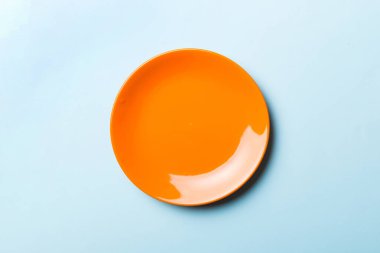 Renkli arka plan izole edilmiş üst görünüm yiyecek için boş yuvarlak orenge plaka. Tasarımınız için alanı olan boş tabak.