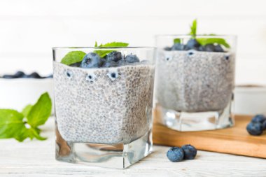 Sağlıklı kahvaltı ve chia tohumlu vanilyalı puding ve böğürtlenli masa arkası, vejetaryen gıda, diyet ve sağlık konsepti. Hindistan cevizi sütü ve yabanmersinli Chia pudingi..