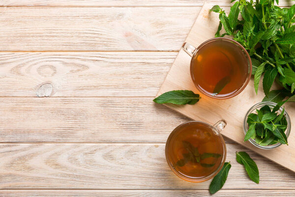 Чашка мятного чая на фоне стола. Зеленый чай со свежим мятным видом сверху с копировальным пространством.