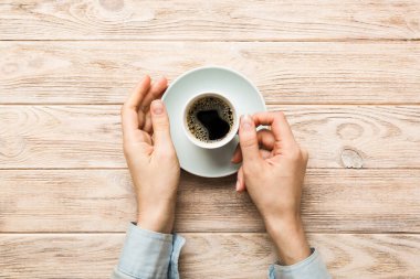 Renkli arka planda bir fincan kahve tutan minimalist stil bir kadın. Düz yerde, kapuçino bardağının üstünde. Metin için boş yer, kopyalama alanı. Kahve bağımlılığı. Üst manzara, düz uzanma.