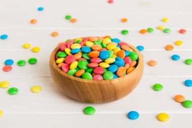 Renkli arka planda bir kasede çok renkli şekerler. Doğum günü ve tatil konsepti. Kopyalama alanı olan üst görünüm.