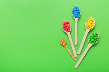 Renkli arka planda kaşık üzerinde renkli tatlı şekerler. Fotokopi alanı ile şekerleme dekoru üst görünümü.