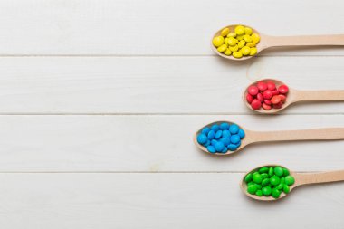 Renkli arka planda kaşık üzerinde renkli tatlı şekerler. Fotokopi alanı ile şekerleme dekoru üst görünümü.