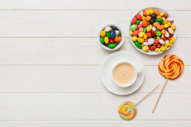 Coffee cup with chocolates and colored candy. Top view on table background with copy space.