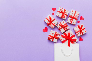 Gift boxes pop out from paper bag top view on colored background. bag packing handmade boxes fall out Concept of holidays, shopping, sale, discounts. Top view, flat lay.