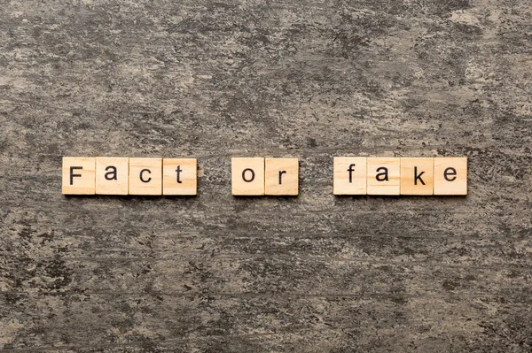 fact or fake word written on wood block. fact or fake text on table, concept.