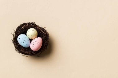Colorful easter eggs in nest on table background with copy space top view.
