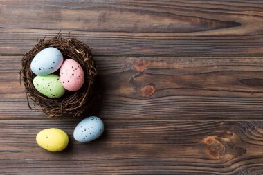 Colorful easter eggs in nest on table background with copy space top view.