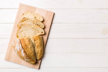 Tahtayı keserken beyaz ahşap zemin üzerinde taze pişmiş ekmek dilimleri. Üst görünüm Dilimlenmiş ekmek.