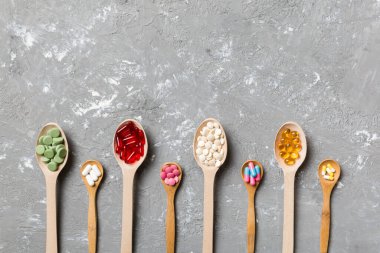 Renkli arka planda tahta kaşıkta vitamin ve mineral haplarının üst görünümü. Muhtelif ilaç haplarının en üst görüntüsü. Beslenme takviyesi sağlık ürünleri.