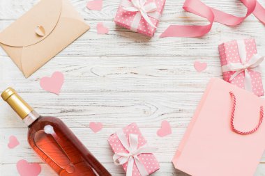 top view photo of st valentine day decor shopping, bag, wine, bottle, envelope, gift, box, candy and red heart on colored background with empty space. Frame background.