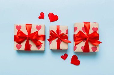 Top view photo of valentine day decorations gift box with red ribbon bow on colored background. Holiday gift boxes with top view.