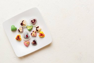 Plate with different chocolate on colored background. Assortment of fine chocolates top view vith copy space Health and obesity concept.
