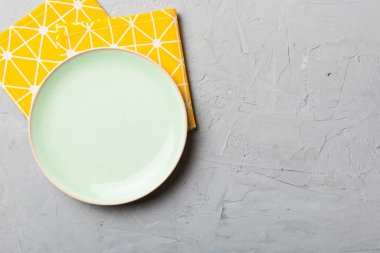 Renkli arka planda üst görünüm yiyecek için masa örtüsünün üzerinde boş yuvarlak yeşil tabak. Tasarımınız için boşluk olan peçeteye boş tabak.