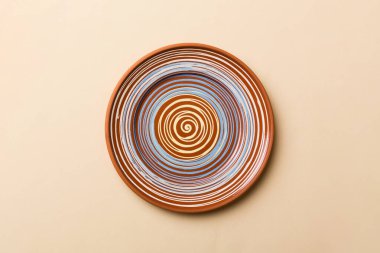 Renkli arka plan görüntüsünün üst görüntüsü yiyecek için boş yuvarlak kahverengi tabak. Tasarımınız için alanı olan boş tabak.