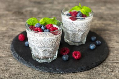 Sağlıklı kahvaltı ya da sabah chia tohumlu vanilyalı puding ahududu ve böğürtlen, vejetaryen gıda, diyet ve sağlık konsepti. Ahududu ve yabanmersinli Chia pudingi..