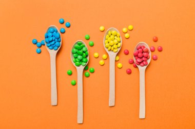 Renkli arka planda kaşık üzerinde renkli tatlı şekerler. Fotokopi alanı ile şekerleme dekoru üst görünümü.