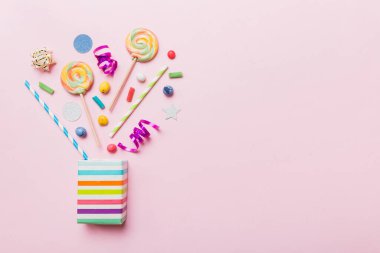 gift box in corner full of assorted traditional candies falling out on colored background with copy space. Happy Holidays sale concept.