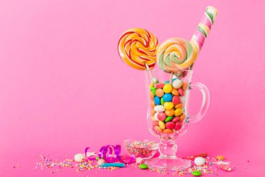 Masanın üzerinde açık arkaplanda renkli şekerler. Büyük kıvrımlı lolipoplar. Şekerci dükkanından leziz şekerlerle dolu yaratıcı bir kavanoz konsepti.