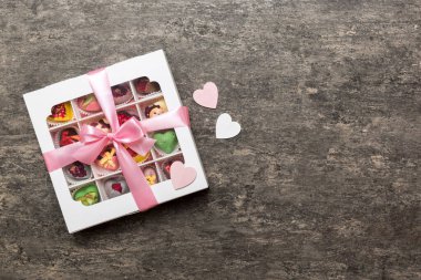 Valentine day composition: sweet candy, with gift boxes with bow and red felt hearts, photo template, background. Top View with copy space.