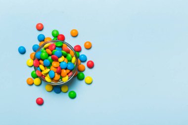 Renkli arka planda bir kasede çok renkli şekerler. Doğum günü ve tatil konsepti. Kopyalama alanı olan üst görünüm.