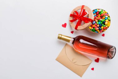 Sevgililer Günü için renkli arka planda bir şişe kırmızı şarap hediye ve çikolatalı. Kalp, hediye kutusuyla şekillendirilmiş çikolatalar fotokopi alanı ile üst görünüm.