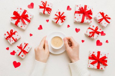 Flat lay of heart shaped cup of black coffee in the hands of women on colored background with copy space top view. Valentine day and holiday concept.