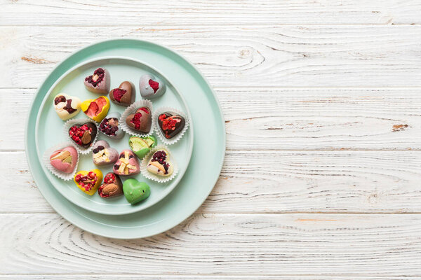 Plate with different chocolate on colored background. Assortment of fine chocolates top view vith copy space Health and obesity concept.