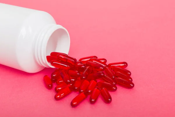 different drugs and health supplement pills poured from a medicine bottle health care and medical top view on colored background.