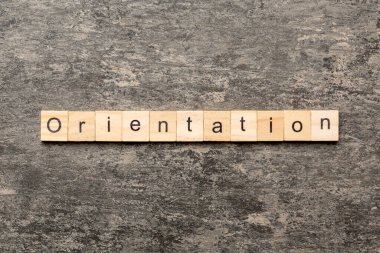 Tahta blokta oryantasyon kelimesi yazıyor. Deksing, konsept için çimento tablo üzerinde oryantasyon metni.