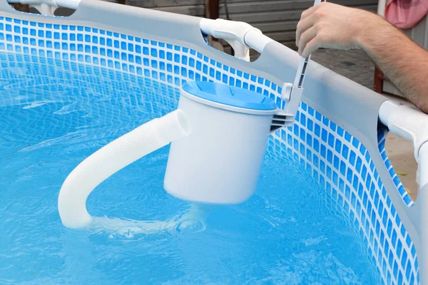 Man cleans skimmer for the frame pool. Contaminated pool cleaning concept.