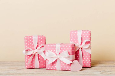 gift box with red bow and red heart on colored background. Perspective view. Flat lay.
