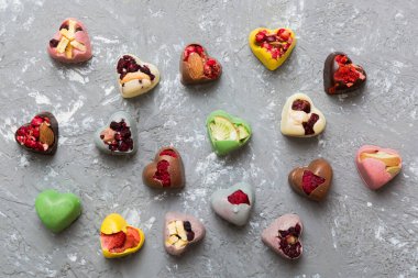 chocolate sweets in the form of a heart with fruits and nuts on a colored background. top view with space for text, holiday concept.