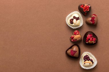 chocolate sweets in the form of a heart with fruits and nuts on a colored background. top view with space for text, holiday concept.