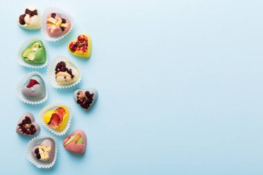 chocolate sweets in the form of a heart with fruits and nuts on a colored background. top view with space for text, holiday concept.