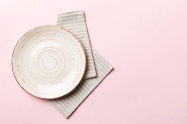 Renkli arka planda üst görünüm yiyecek için masa örtüsü üzerindeki boş yuvarlak beyaz tabak. Tasarımınız için boşluk olan peçeteye boş tabak.
