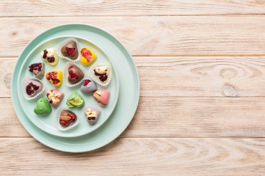 Plate with different chocolate on colored background. Assortment of fine chocolates top view vith copy space Health and obesity concept.