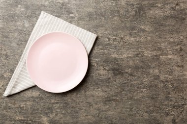 Renkli arka planda üst manzara. Yemek için masa örtüsü üzerine yuvarlak pembe tabak. Tasarımınız için boşluk olan peçeteye boş tabak.