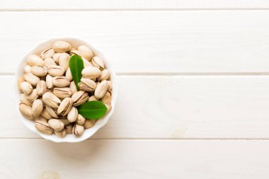 Fresh healthy Pistachios in bowl on colored table background. Top view. Healthy eating concept. Super foods.