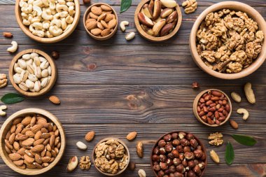 mixed nuts in wooden bowl. Mix of various nuts on colored background. pistachios, cashews, walnuts, hazelnuts, peanuts and brazil nuts.