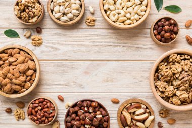 mixed nuts in wooden bowl. Mix of various nuts on colored background. pistachios, cashews, walnuts, hazelnuts, peanuts and brazil nuts.