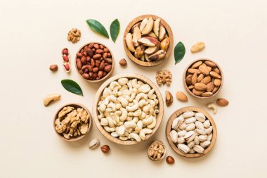mixed nuts in wooden bowl. Mix of various nuts on colored background. pistachios, cashews, walnuts, hazelnuts, peanuts and brazil nuts.