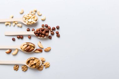 mixed nuts in white wooden spoon. Mix of various nuts on colored background. pistachios, cashews, walnuts, hazelnuts, peanuts and brazil nuts.