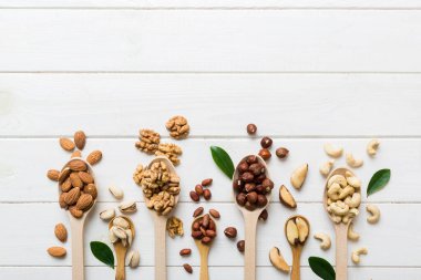 mixed nuts in white wooden spoon. Mix of various nuts on colored background. pistachios, cashews, walnuts, hazelnuts, peanuts and brazil nuts.