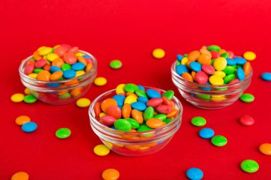 Renkli arka planda bir kasede çok renkli şekerler. Doğum günü ve tatil konsepti. Kopyalama alanı olan üst görünüm.