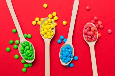 Renkli arka planda kaşık üzerinde renkli tatlı şekerler. Fotokopi alanı ile şekerleme dekoru üst görünümü.