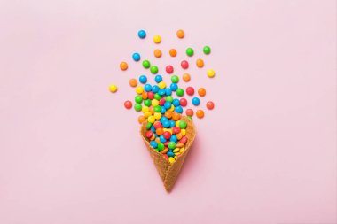 waffle cone full of assorted traditional candies falling out on colored background with copy space. Happy Holidays sale concept.